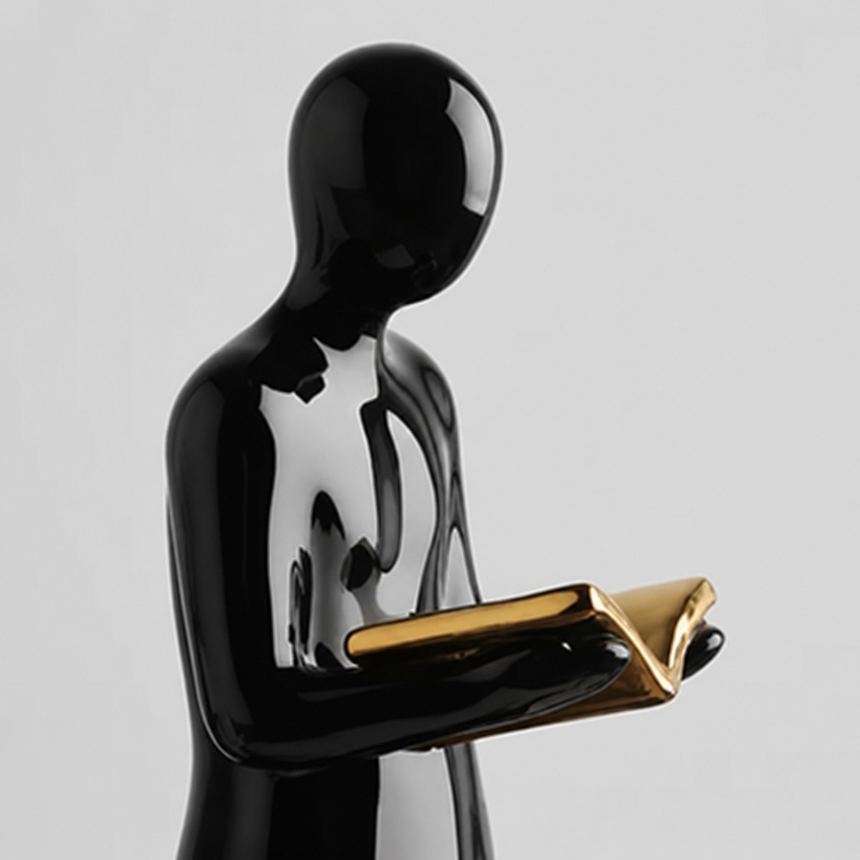 Detalle de una figura de cerámica negra brillante de pie leyendo