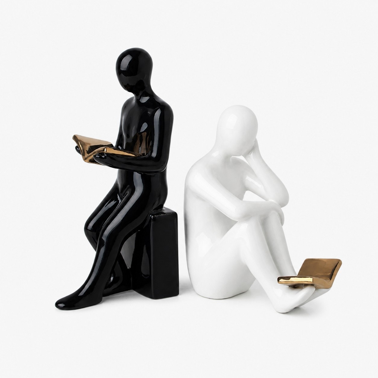 Figura negra de pie y figura blanca leyendo como sujetalibros de cerámica