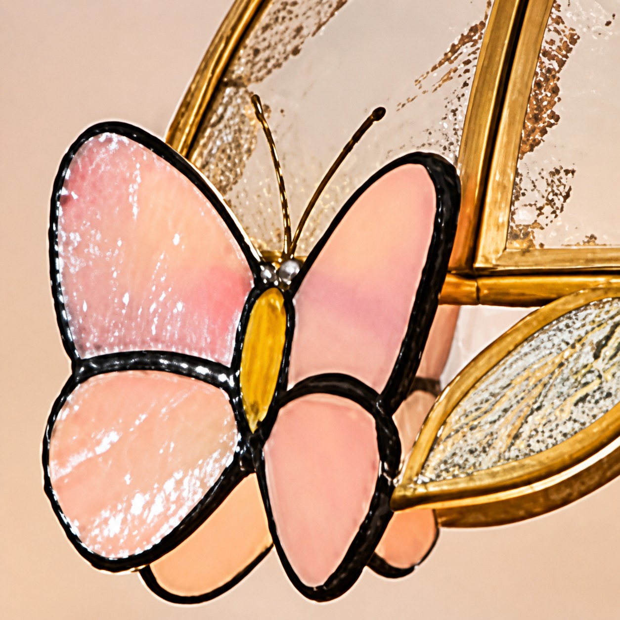 Close view of the pink butterfly stained glass motif with black leading and brass shade frame