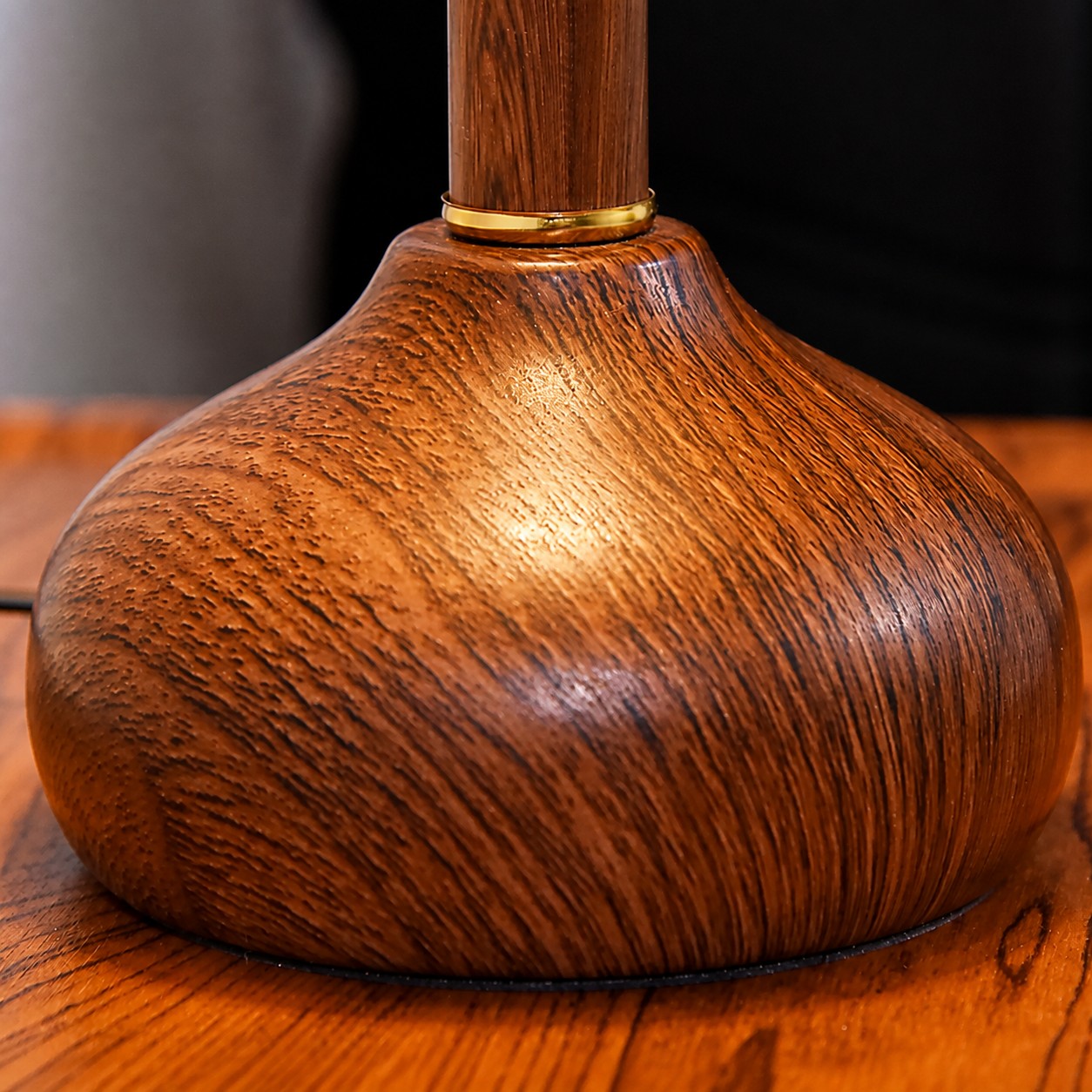 Close view of the wood grain lamp base and brass collar